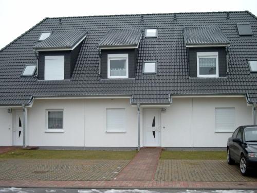 ein Haus mit weißen Türen und einem schwarzen Dach in der Unterkunft Ferienwohnung Usedom Ostseebad Zempin in Zempin