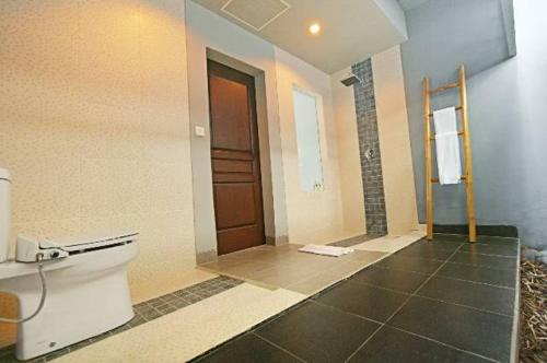 a bathroom with a toilet and a brown door at The Grey Boutique Inn in Legian