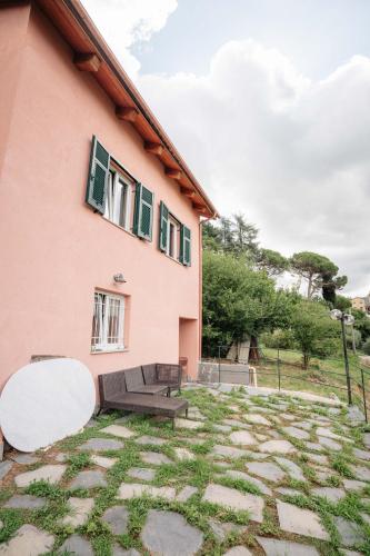 a pink house with a bench and a patio at 8 beds- surrounded by greenery with parking in Uscio