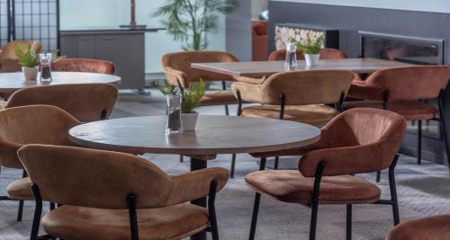 a room with tables and chairs and a fireplace at Cambridge Bar Hill Hotel, BW Signature Collection in Cambridge