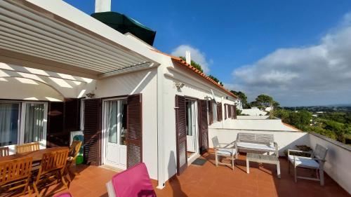 a balcony of a house with chairs and a table at Casa Feliz Obidos Lagoon and sea view in Foz do Arelho