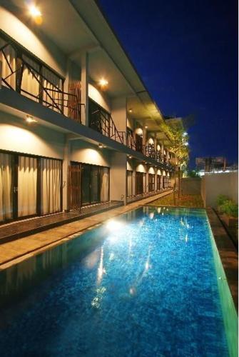 a swimming pool in front of a building at night at The Grey Boutique Inn in Legian