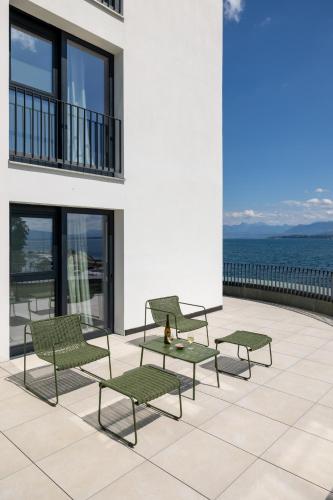 a group of chairs and tables on a patio overlooking the ocean at Maison du Lac Boutique Hôtel in Nyon