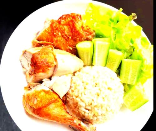 a white plate of food with chicken rice and vegetables at Bati Valley Guest House in Kigali