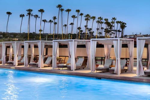 a pool with white chairs and a marquee and palm trees at La Jolla Beach & Tennis Club in San Diego