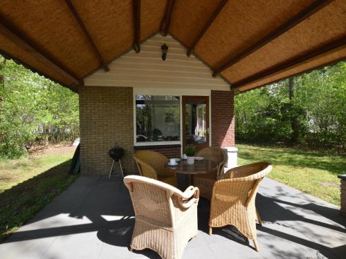 a patio with wicker chairs and a table at Romantic Forest Retreat with Sauna in Stramproy