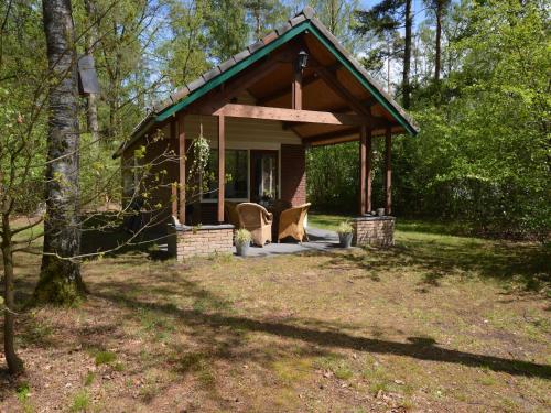 a small cabin in the woods with two chairs in front at Romantic Forest Retreat with Sauna in Stramproy