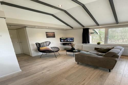 a living room with a couch and a chair at Romantic Forest Retreat with Sauna in Stramproy