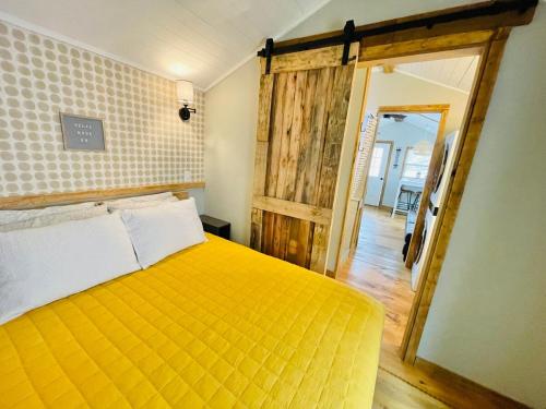 a bedroom with a yellow bed and a wooden door at Misty Hollow Tiny Home Cottage in Robbinsville