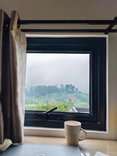 a coffee cup sitting on a table in front of a window at Luma Senja Villa WFA, WFH, Workspace & Honeymoon Puncak Dua in Cikuray
