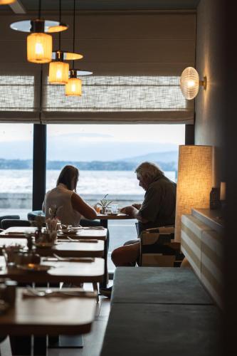 a group of people sitting at tables in a restaurant at Maison du Lac Boutique Hôtel in Nyon
