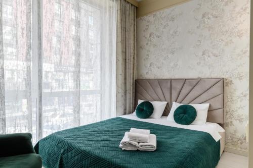 a bedroom with a green bed with towels on it at 4You apartments 2 in Almaty