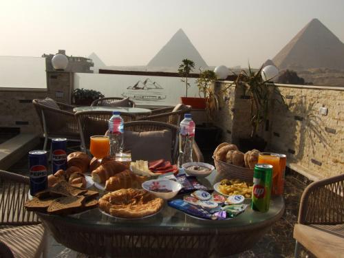a table with food and drinks and the pyramids at Pyramids Khufu Solar Boat Hotel in Cairo