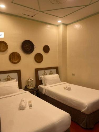 a room with two beds and two plates on the wall at Park Avenue Boutique Hotel Manila in Manila