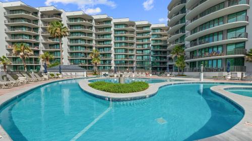 a swimming pool in front of a large apartment building at Enjoy a 3-bedroom Bayfront Condo with Lazy River Indoor Pool Jacuzzis and Community Boat Dock for Personal or Rented Boats Plus Redeem in Free Activity Deals Daily in Orange Beach