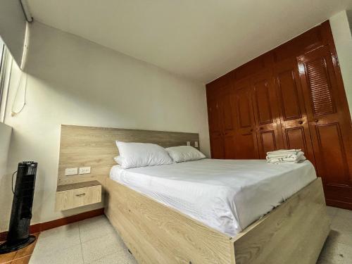 a bedroom with a large bed with a wooden headboard at NEÓN TOLIMA - Hotel en Zona Centro de Ibagué - Recepción y Atención Digital 24H in Ibagué