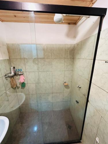 a shower with a glass door next to a sink at House for World Rally-Paraguay in Hohenau