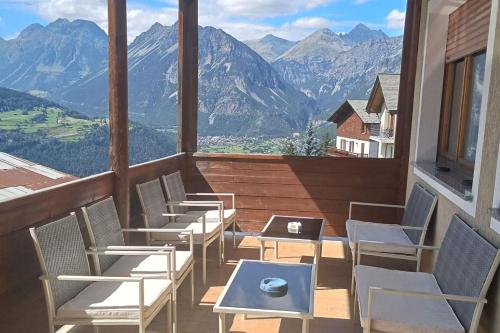 a balcony with chairs and tables and a view of mountains at Albergo Ristorante Ginepro in Bormio