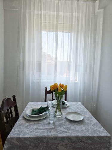 a table with plates and a vase of flowers on it at Stan na dan Centar Čačak in Čačak