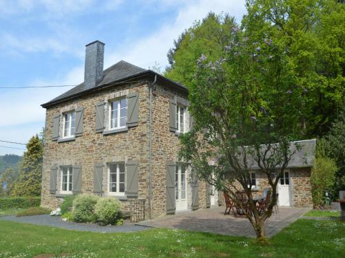 an old stone house with a tree in front of it at Sunny Garden Cottage, Alle in Frahan