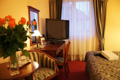 a hotel room with a bed and a desk with a television at Hotel Wellness & Spa Nowy Dwór in Rzeszów