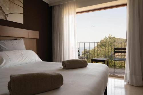 a bedroom with a bed and a large window at Maristel Hotel & Spa - Adults Only in Estellencs