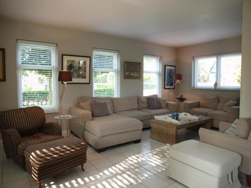 ein Wohnzimmer mit Sofas und Stühlen und Fenstern in der Unterkunft Groet Villa Stay with Garden Views in Groet