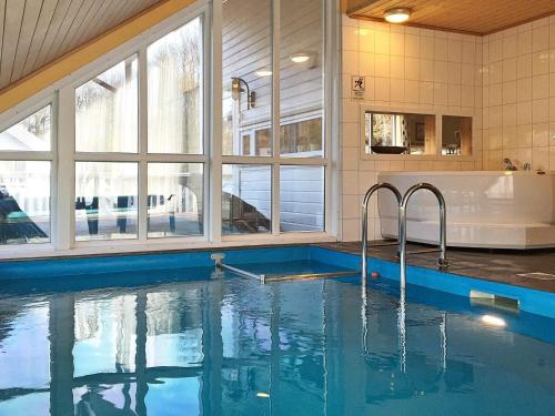 a swimming pool in a house with a tub and windows at 4 star holiday home in Auklandshamn in Vestvik