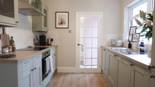 a kitchen with white cabinets and a large window at Luxury living outside the city walls - sleeps six! in Chester