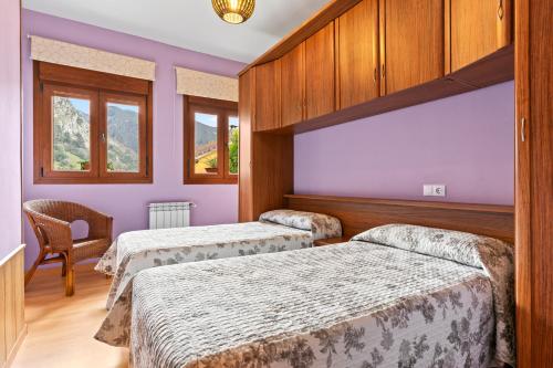 two beds in a room with purple walls and windows at Apartamentos Les Cuartes in Cangas de Onís