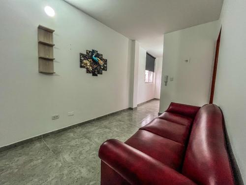 a red couch in a living room with a clock on the wall at NEÓN TOLIMA - Hotel en Zona Centro de Ibagué - Recepción y Atención Digital 24H in Ibagué