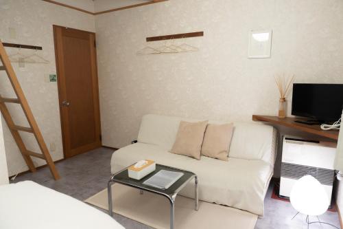 a living room with a white couch and a table at 歩絵夢の森 Pension Poem no mori in Hakuba