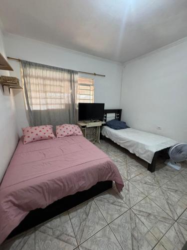 a bedroom with two beds and a desk at Chacara Oliva in Piracicaba