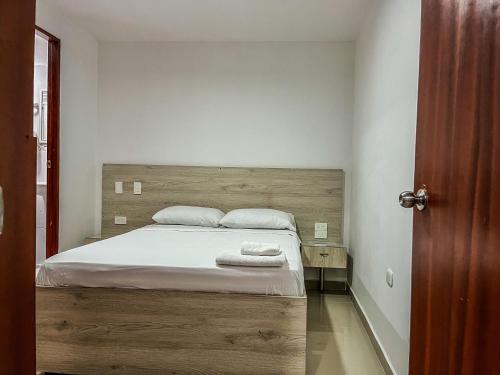 a bedroom with a bed with a wooden headboard at NEÓN TOLIMA - Hotel en Zona Centro de Ibagué - Recepción y Atención Digital 24H in Ibagué