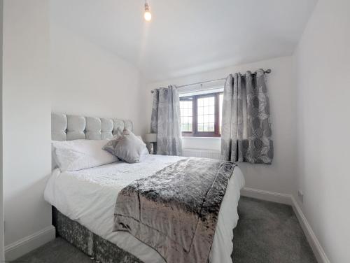 a white bedroom with a large bed and a window at Creek House with Hot Tub - Coming Soon in South Hayling