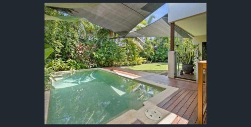 a swimming pool in a backyard with an umbrella at Entire 4 bedroom home in Palm Cove in Palm Cove