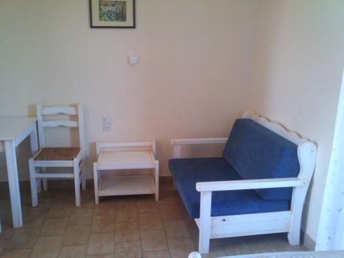 a living room with a blue couch and two chairs at Aenaon Studios in Oreoí