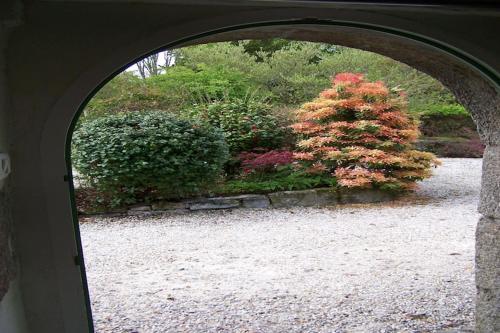 an arched doorway to a garden with a flowering bush at Holiday Home in Huelgoat near Monts d'Arrée in Huelgoat