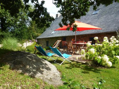 a patio with a table and chairs and an umbrella at Holiday Home in Huelgoat near Monts d'Arrée in Huelgoat