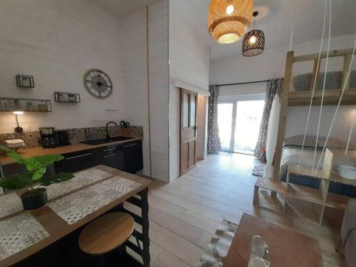 a kitchen and living room with a table and a bed at Le lodge - appartement 4 personnes proche mer in Bréhal