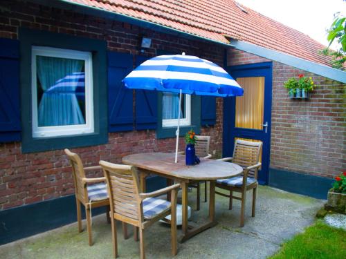 a table and chairs with a blue umbrella at Farmhouse in Nederweert near Canal Trails in Ospel