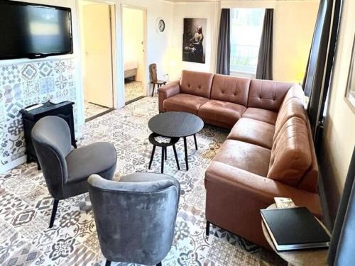 a living room with a brown leather couch and chairs at Farmhouse in Nederweert near Canal Trails in Ospel