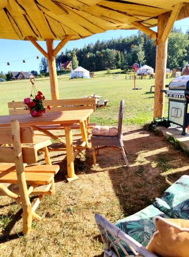 a wooden picnic table and chairs under a pavilion at Glamping Niebiańska Osada Jurty Dolnośląskie & SPA in Polanica-Zdrój
