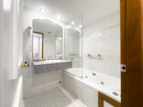 a bathroom with a tub and a sink and a mirror at Patagonia Plaza Hotel in San Martín de los Andes