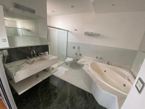 a bathroom with a tub and a toilet and a sink at Anacã SC in São Carlos