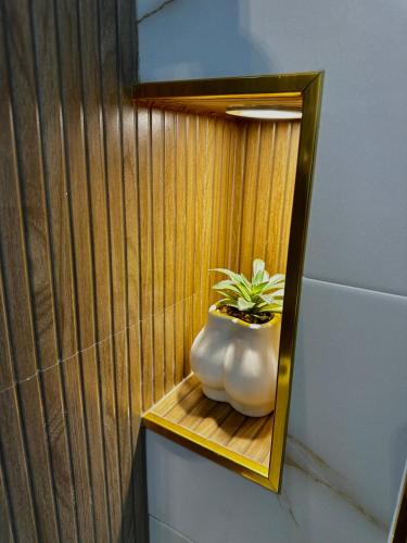 a plant in a white vase sitting on a wooden shelf at AP Rooms in Almorox