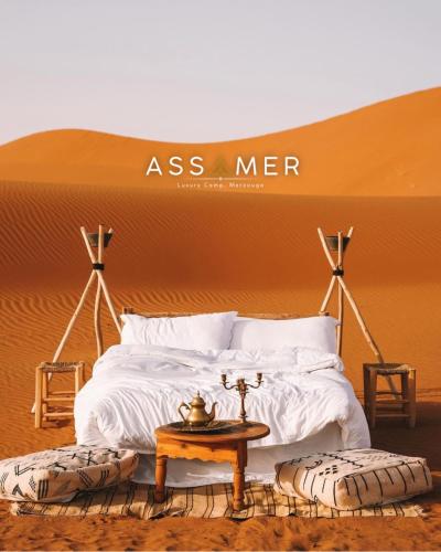 メルズーガにあるAssamer Luxury Campの砂漠にあるベッドとテーブルのある寝室