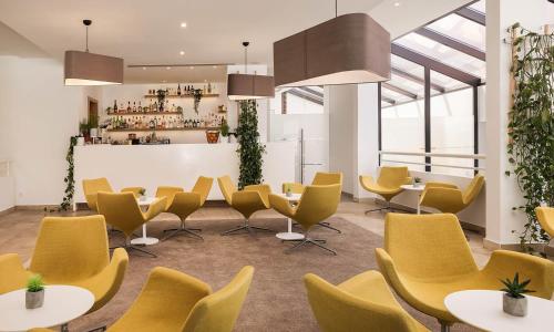 a room with yellow chairs and tables and a bar at Aminess Younique Liburna Hotel in Korčula