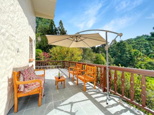 un patio avec deux chaises et un parasol dans l'établissement 2 suítes Lareira Jacuzzi Churrasqueira, à Campos do Jordão