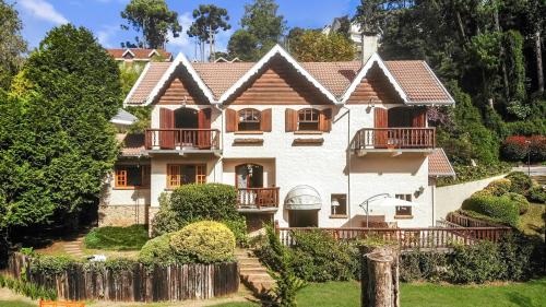 Cette grande maison blanche dispose d'un balcon et d'une cour. dans l'établissement 2 suítes Lareira Jacuzzi Churrasqueira, à Campos do Jordão